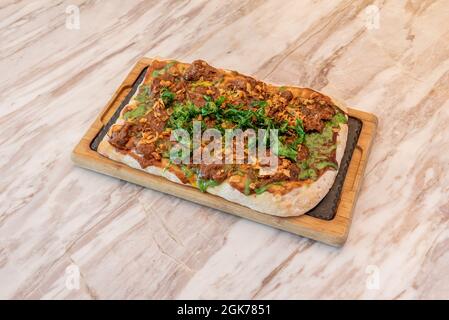 Rechteckige Grillpizza mit geschreddertem Rindfleisch, knuspriger Zwiebel und gebratener Rucola Stockfoto