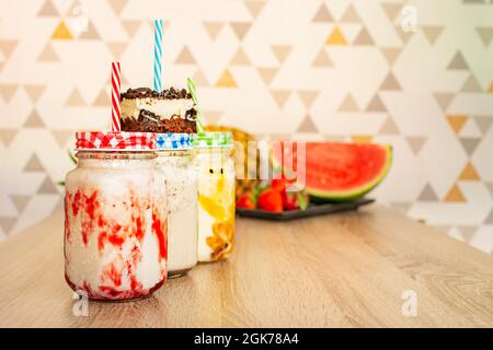 Obst- und Schokoladen-Smoothies mit Erdbeeren, reifen Ananas, Wassermelone und Passionsfrucht auf Holztisch Stockfoto