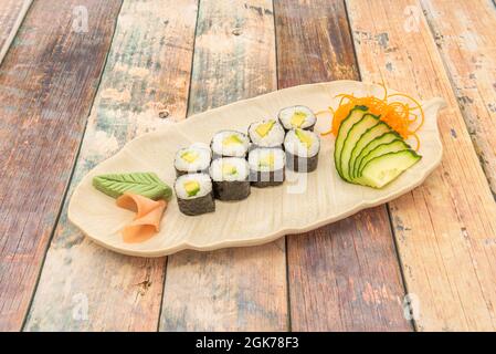 Acht Portionen Avocado Maki Roll mit Wasabi, Ingwer, Gurke und Karotte auf weißem Teller Stockfoto