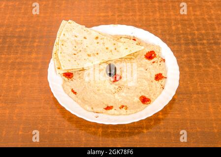 baba ganoush mit Pitabrot, schwarzen Oliven und Paprika auf einem weißen Teller Stockfoto