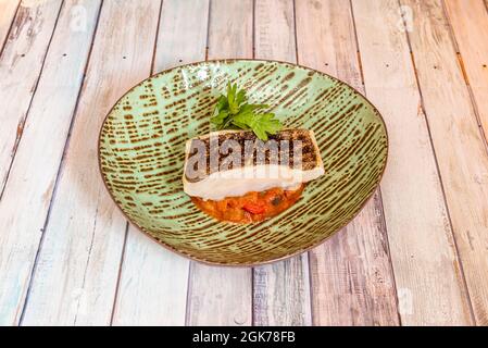 Taco von Confit Kabeljau auf einem Hintergrund von Pisto manchego in einem schönen grünen Teller Stockfoto