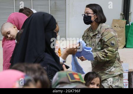 Ein Soldat der US-Armee der Nationalgarde mit der Task Force Spartan, US Army Central, unterstützt Familien, die vor kurzem aus Afghanistan evakuiert wurden, als sie am 23. August 2021 in Camp Buehring, Kuwait, eintreffen. Soldaten der US-Armee arbeiten weiterhin mit ihren Teamkollegen des US-Hauptkommandos und des Außenministeriums zusammen, um die Evakuierungsbemühungen in Afghanistan durch Transport, Sicherheit, Logistik und medizinische Hilfe an Standorten in Kuwait zu unterstützen. Stockfoto