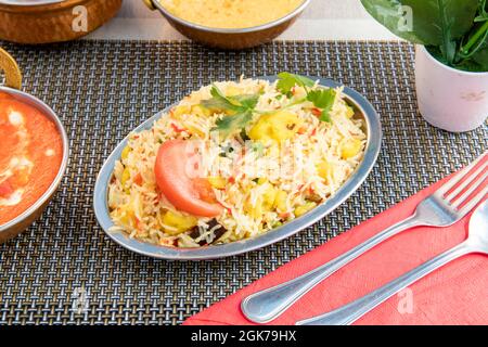 Tablett mit Biryani-Reis mit frischem Gemüse in einem Indu-Restaurant mit Besteck und Decken gekocht Stockfoto