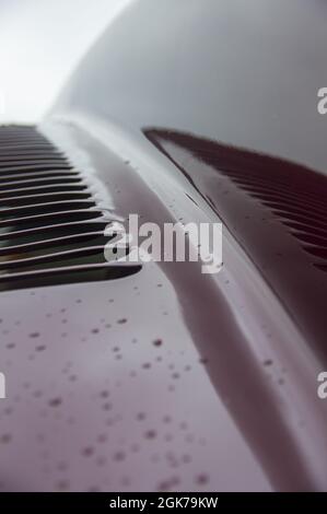 Abstrakt Kunst Textur Hintergrund von Regentropfen auf braun rot glänzend gebürsteten Edelstahl-Metalloberfläche auf alten Retro-Oldtimer Dach und Stoßstange Stockfoto