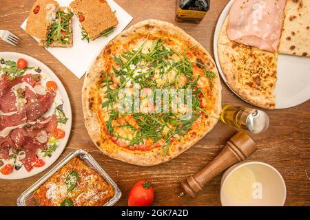 Bild von Pizzas und typisch italienischen Gerichten aus der Sicht von oben mit Salz, Pfeffer und Carpacio auf einem Holztisch Stockfoto