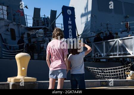 Familienmitglieder winken Matrosen an Bord des Arleigh Burke-Klasse-Lenkflugkörper-Zerstörers USS John Paul Jones (DDG 53) zu, als es am 23. August 2021 in seinem neuen Heimathafen am Marinestützpunkt Everett in Everett, Washington, ankommt. John Paul Jones ist Teil der Nimitz Carrier Strike Group und wurde früher in Pearl Harbor, Hawaii, gegründet. Stockfoto