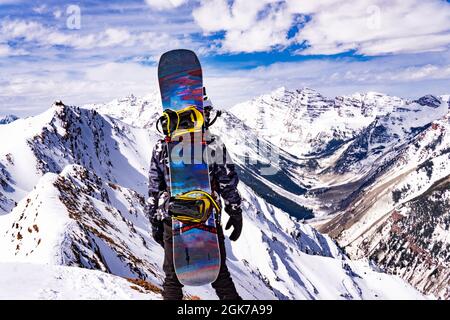 Mann Mit Snow Board Auf Dem Rücken In Extreme Snow Mountain Landscape Summit Stockfoto