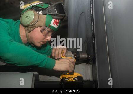 210824-N-UF592-1045 ARABIAN SEA (AUG 24, 2021) – Aviation Structural Mechanic 2nd Class Nathan French, führt Wartungsarbeiten am Flügel eines F/A-18F Super Hornet Kampfjets durch, der an den „Diamondbacks“ des Strike Fighter Squadron (VFA) 102 in der Hangarbucht des Flugzeugträgers Ronald USS Reagan (CVN 76) im Arabischen Meer angebracht ist, 24. August. Ronald Reagan ist das Flaggschiff der Carrier Strike Group 5 und wird im Einsatzgebiet der 5. US-Flotte eingesetzt, um die maritime Stabilität und Sicherheit in der Zentralregion zu gewährleisten, wobei das Mittelmeer und der Pazifik durch die Verbindung miteinander verbunden werden Stockfoto