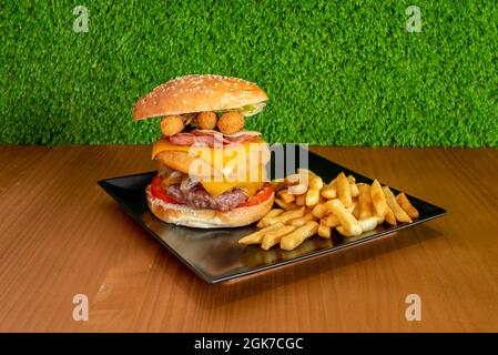 Knusprige, doppelt gemischte Hamburger mit Hühnchen und Rindfleisch, Double Cheddar-Käse und Mozzarella-Sticks, Speck, geschmorte Zwiebeln mit Beilage-Pommes frites Stockfoto