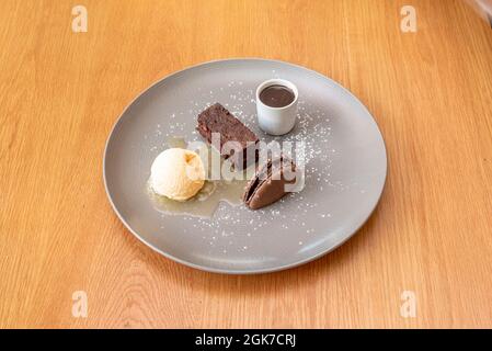 Schokoladenbrownie-Dessert, mit Makronen-Keks, Vanilleeis, dunkler Schokoladencreme und Honigsirup Stockfoto