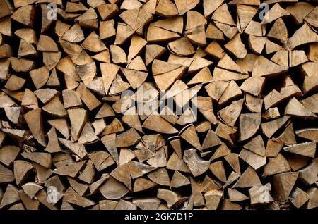 Getrocknetes Buchenholz bereit zum Erhitzen. Holzstapel im Stapel. Dreieckige Form. Gehacktes Brennholz, auf einem Haufen getrocknet. Hintergrundstruktur aus Holz. Stockfoto