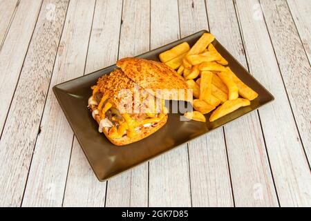 Mexikanischer Burger mit Frischkäse und geschmolzenem Cheddar-Käse, knusprig gebratener Zwiebel, Knoblauchbrot und geschmolzenem Käse, garniert mit Pommes frites Stockfoto