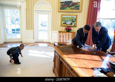 Präsident Barack Obama signiert ein Plakat für den 13-jährigen Studenten Vidal Chastanet, der auf dem Blog "Menschen von New York" erschien, als sein 6-jähriger Bruder Alden St. Marie am 5. Februar 2015 links im Oval Office spielt. (Offizielles Foto des Weißen Hauses von Pete Souza) Dieses offizielle Foto des Weißen Hauses wird nur zur Veröffentlichung durch Nachrichtenorganisationen und/oder zum persönlichen Druck durch die Betreffzeile(en) des Fotos zur Verfügung gestellt. Das Foto darf in keiner Weise manipuliert werden und darf nicht in kommerziellen oder politischen Materialien, Anzeigen, E-Mails, Produkten, Werbeaktionen, die in irgendeiner Form verwendet werden Stockfoto