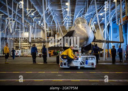 210828-N-SY758-1034 ATLANTIK (AUG 28, 2021) die erste Klasse Carlos Sanchez aus New York, die dem Luftverkehrsministerium auf dem Flugzeugträger USS George H. W. Bush (CVN 77) zugewiesen wurde, bewegt ein Trainingsflugzeug durch die Hangarbucht, um sich auf eine schnelle Ruderprüfung während der Sea Trials vorzubereiten. Das Schiff ist im Atlantischen Ozean im Einsatz, um die maritime Stabilität und Sicherheit zu erhalten, um den Zugang zu gewährleisten, Aggressionen abzuwehren und die Interessen der USA, der Alliierten und der Partner zu verteidigen. Stockfoto