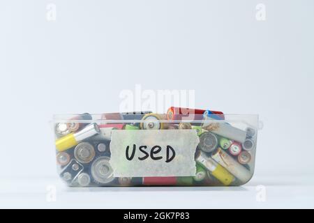 Nahaufnahme der gebrauchten Batterie im Kunststoffbehälter über der weißen Wand. Konzept für gefährliche elektronische Abfälle. Stockfoto