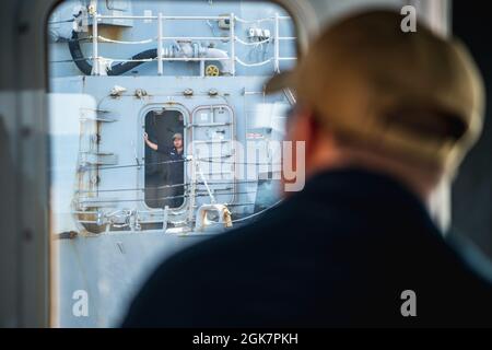 YOKOSUKA, Japan (Aug 28, 2021) – Ein Besatzungsmitglied an Bord des geführten Raketenzerstörers der Arleigh Burke-Klasse, USS Stockdale (DDG 106), blickt auf die Yard Tug Seminole (YT-805), während sie das Schiff zu einem Liegeplatz bei Commander, Fleet Activities Yokosuka für einen planmäßigen Hafenbesuch führt. Stockdale, das in San Diego, Kalifornien, stationiert ist, und die zugehörige Carrier Strike Group (CSG 1) befinden sich im operativen Bereich der 7. US-Flotte im Rotationseinsatz, um die Interoperabilität mit Partnern zu verbessern und als einsatzbereite Kraft zur Unterstützung einer freien und offenen Region im Indo-Pazifik-Raum zu fungieren. Stockfoto