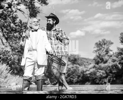 Angeln. Fliegenfischen Abenteuer. Rentner Vater und reifer Sohn mit Bart. Freunde Männer mit Angelrute und Netz. Glückliche Fischer im Wasser. Hobby Stockfoto