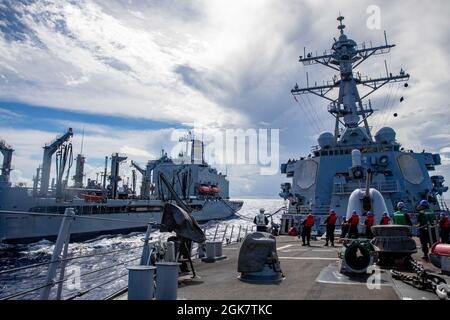 PHILIPPINISCHES MEER (Aug 29, 2021) der Lenkrakenzerstörer USS Barry (DDG 52) der Arleigh Burke-Klasse führt während MALABAR 2021 eine Auffüllung auf See mit dem Trockenfrachtschiff USNS Yukon (T-AO 202) der Henry J. Kaiser-Klasse durch. Barry wird derzeit zur Unterstützung von Commander, Task Force (CTF) 71/Destroyer Squadron (DESRON) 15, der größten vorwärtseingesetzten DESRON der Marine und der wichtigsten Surface Force der US-Flotte der 7. Flotte eingesetzt. Stockfoto