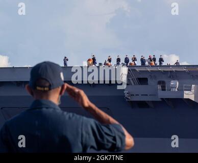 PHILIPPINISCHES MEER (Aug 29, 2021) Ein Seemann an Bord der Arleigh Burke-Klasse, der Lenkrakenzerstörer USS Barry (DDG 52), ehrt während MALABAR 2021 den Hubschrauberträger JS Kaga (DDH 184) der Izumo-Klasse der Japan Maritime Self-Defence Force. Barry wird derzeit zur Unterstützung von Commander, Task Force (CTF) 71/Destroyer Squadron (DESRON) 15, der größten vorwärtseingesetzten DESRON der Marine und der wichtigsten Surface Force der US-Flotte der 7. Flotte eingesetzt. Stockfoto