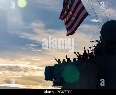 PHILIPPINISCHES MEER (Aug 29, 2021) Seeleute an Bord der Arleigh Burke-Klasse des Lenkraketenzerstörers USS Barry (DDG 52) verabschiedeten sich am Ende von MALABAR 2021 von der Royal Australian Navy HMAS Warramunga zusammen mit Schiffen der Japan Maritime Self-Defense Force und der Indian Navy. Barry wird derzeit zur Unterstützung von Commander, Task Force (CTF) 71/Destroyer Squadron (DESRON) 15, der größten vorwärtseingesetzten DESRON der Marine und der wichtigsten Surface Force der US-Flotte der 7. Flotte eingesetzt. Stockfoto