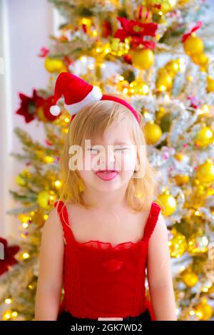 Mädchen mit einem Hut des Weihnachtsmanns steht in Neujahrsdekorationen Stockfoto