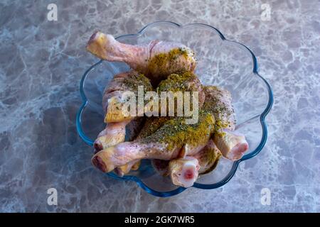 Rohe Hähnchenschenkel mit verschiedenen Gewürzen gemischt. Ungekochte Hähnchendrumsticks werden zum Kochen zubereitet. Stockfoto