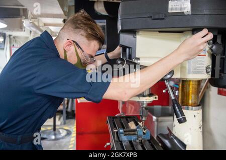 210831-N-MD461-1136 PACIFIC OCEAN (31. August 2021) Aviation Structural Mechanic Airman Lancelot White, ein gebürtiger aus Springfield, Missouri, bohrt an Bord des Flugzeugträgers USS Carl Vinson (CVN 70) der Nimitz-Klasse einen Bolzen in der Flugzeugwerkstatt, 31. August 2021. Die Carl Vinson Carrier Strike Group ist im Einsatzgebiet der 7. Flotte der USA im Einsatz, um die Interoperabilität mit Verbündeten und Partnern zu verbessern und als einsatzbereite Truppe zur Unterstützung einer freien und offenen Region im Indo-Pazifik-Raum zu fungieren. Stockfoto