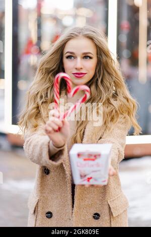 Fröhliches Mädchen mit herzförmigen Lutschern auf einem Weihnachtsmarkt Stockfoto