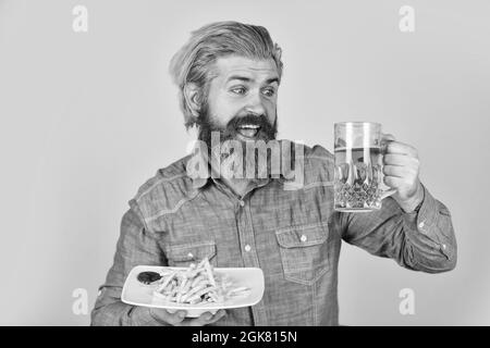 Prost. beim Fußballschauen im Fernsehen. amerikanisches Fast Food. Glücklicher bärtiger Mann mit Bier und pommes frites. Pommes Frites Kartoffel. Kerl in der amerikanischen Bar trinken Stockfoto