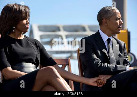 Präsident Barack Obama und First Lady Michelle Obama halten die Hände fest, während sie dem Republikaner John Lewis, D-Georgia, während einer Veranstaltung zum Gedenken an den 50. Jahrestag des Blutigen Sonntags und der Bürgerrechtsmärsche von Selma nach Montgomery, an der Edmund Pettus Bridge in Selma, Alabama, 7. März 2015, zuhören. (Offizielles Foto des Weißen Hauses von Pete Souza) Dieses offizielle Foto des Weißen Hauses wird nur zur Veröffentlichung durch Nachrichtenorganisationen und/oder zum persönlichen Druck durch die Betreffzeile(en) des Fotos zur Verfügung gestellt. Das Foto darf in keiner Weise manipuliert werden und darf nicht in kommerziellen oder politischen Matten verwendet werden Stockfoto