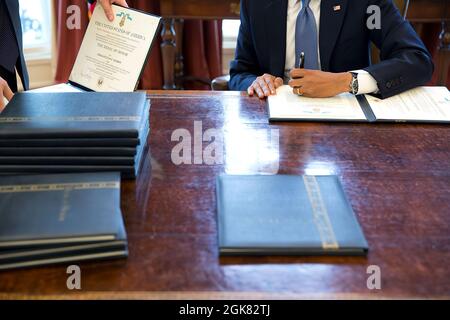 Präsident Barack Obama unterschreibt im Oval Office Zitate zur Ehrenmedaille, 17. März 2014. (Offizielles Foto des Weißen Hauses von Pete Souza) Dieses offizielle Foto des Weißen Hauses wird nur zur Veröffentlichung durch Nachrichtenorganisationen und/oder zum persönlichen Druck durch die Betreffzeile(en) des Fotos zur Verfügung gestellt. Das Foto darf in keiner Weise manipuliert werden und darf nicht in kommerziellen oder politischen Materialien, Anzeigen, E-Mails, Produkten oder Werbeaktionen verwendet werden, die in irgendeiner Weise die Zustimmung oder Billigung des Präsidenten, der ersten Familie oder des Weißen Hauses nahelege. Stockfoto