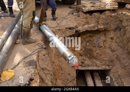 Austausch von Kanalrohren. Verlegung von Gasleitungen in den Boden. Die Mitarbeiter bauen neue Kommunikationswege auf. Bauarbeiten auf der Straße. Stockfoto