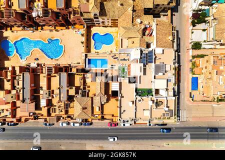 Direkt über Luftaufnahme Wohn typische Häuser mit Schwimmbad und Stadtstraße mit Autos. Provinz Alicante, südlich von Spanien, Costa Blanca. Stockfoto