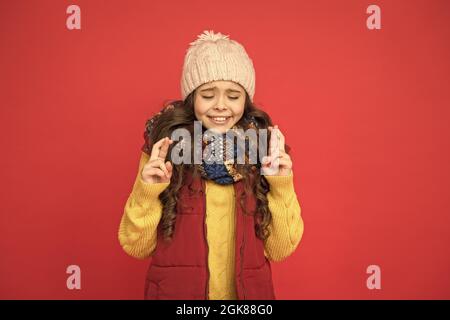 Teen Kind in Kugelweste und Strickmode machen Wunsch. Saisonale Kindermode. weihnachtsurlaub und Urlaub. Nette Schönheit warm halten. Wettervorhersage Stockfoto