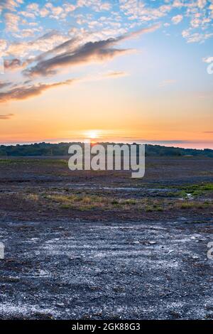 Sonnenaufgang über dem Wald, der in Katowice, Schlesien, Polen, für den Bergbau gesehen wird. Schöne Wolken am bunten Himmel. Kiesstruktur im Vordergrund - Text Stockfoto