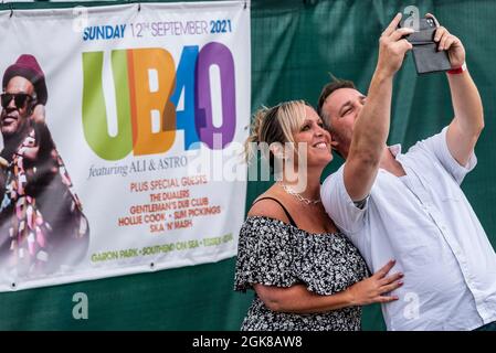 Fans, die zu einem UB40 mit Ali & Astro-Musikkonzertfestival in Garon Park, Southend on Sea, Essex, Großbritannien, kommen. Selfie mit Show-Banner aufnehmen Stockfoto