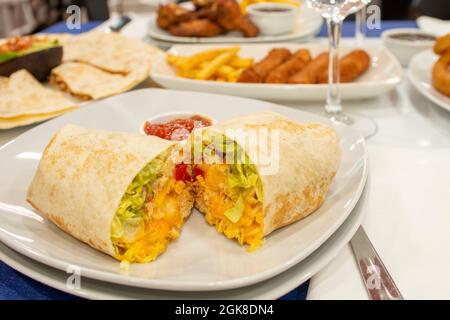 Maistortilla Burrito mit Hühnerfleisch, Salat und Tomaten mit Cheddar-Käse Stockfoto