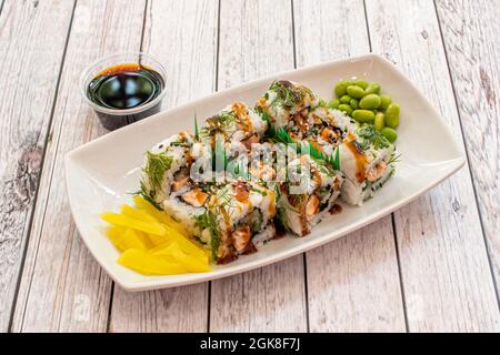 kalifornisches Lachs-Uramaki-Sushi mit Teriyaki-Sauce, Edamame-Bohnen, gelber Paprika, frischem Dill, Sesam und Sojasauce Stockfoto