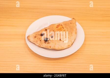 Typisch italienische Calzone gefüllt mit vier Käsesorten auf einem weißen Teller Stockfoto