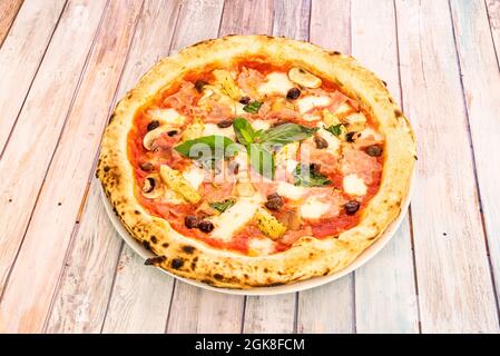 Skurrile italienische Pizza Rezept mit Artischockenherzen, Basilikum, Prosciutto, Schwarzen Oliven, Pilzen, Und Mozzarella-Käse Stockfoto