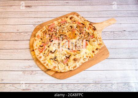 Großes Bild von italienischen Carbonara Rezept Pizza mit viel geschmolzenem Käse, viele Scheiben von frischem Pilz und Gauciale mit Orangano auf Holztisch Stockfoto