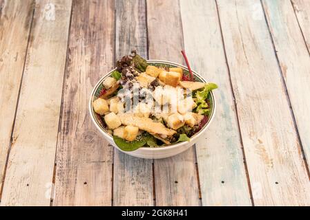 Kleine Schüssel cesar-Salat mit den üblichen Zutaten auf Holzboden Stockfoto