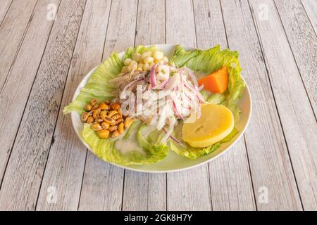 Peruanischen Fisch-Ceviche mit Cancha, Süßkartoffeln, gekochten Kartoffeln, roten Zwiebeln, Saft, Salat auf einem weißen Teller. Stockfoto