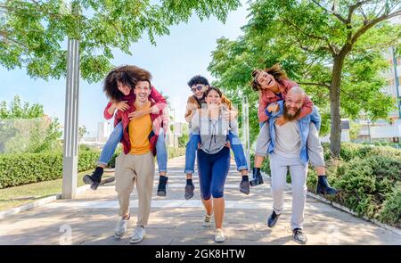 Multiethnische Gruppe von Freunden läuft auf der Straße im Freien lachen und Spaß haben. Diverse Menschen feiern das Leben zusammen genießen frohe Feiertage. Stockfoto