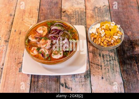 Garnelen Ceviche in großer Menge in einer Glasschale und begleitet von einem kleineren voll peruanischen Cancha auf einem Holztisch Stockfoto