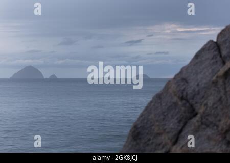 Steinhang im stillen Meer mit Hügelinseln unter bewölktem Himmel an bewölktem Tag in Malaysia Stockfoto