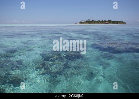 Transparentes, plätscherndes Wasser endlosen Meeres mit sandigen Grund und Insel unter blauem Himmel in Malaysia Stockfoto