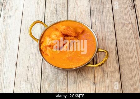 Chicken Tikka Masala serviert im typischen Container des indischen Restaurants auf einem hellen Tisch Stockfoto