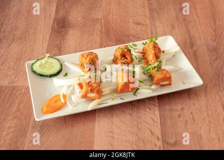 Indische Chicken Tikka Masala Rezept auf Stücke von weißen Zwiebeln, Gurke, Karotte, gehackte Petersilie auf einem weißen Tablett Stockfoto