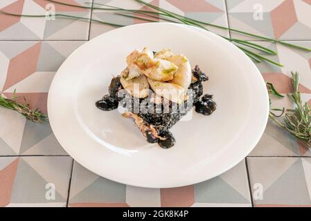 Spanisches Rezept von Tintenfisch, geschmort mit schwarzem Reis auf einem weißen Teller Stockfoto